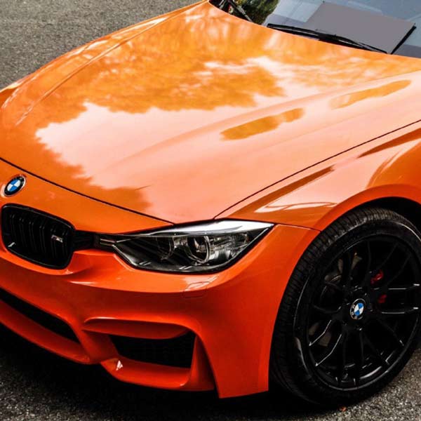 Side view of an orange BMW car with a shiny finish